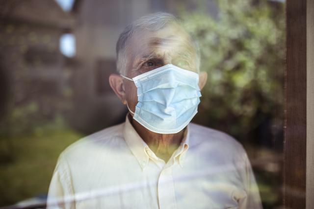 Man in a mask looking out of window