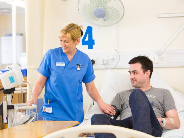 Nurse looking after man in hospital bed