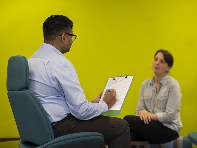 Man taking notes on clipboard in front of woman