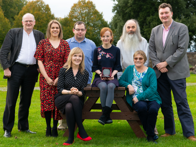 Group of people sat on a bench with award