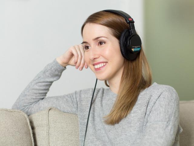 Woman wearing headphones sat on a couch