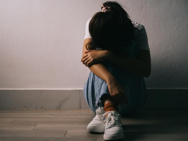 Woman with brown hair sat on floor hanging her head