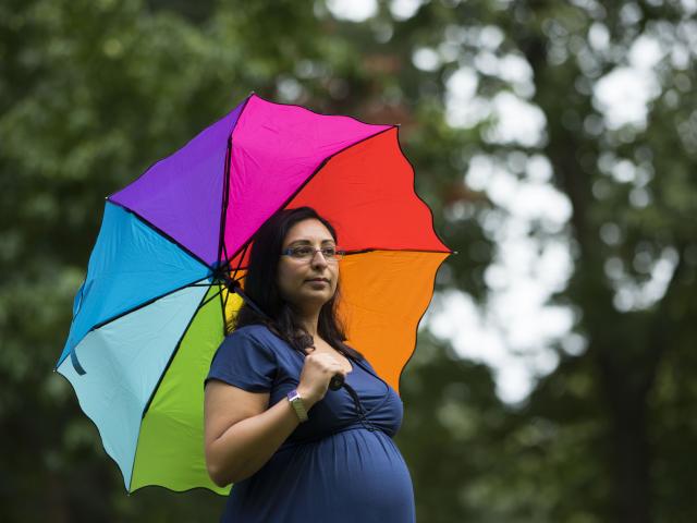 Pregnant woman holding colourful umbrella