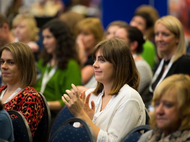 Woman clapping in event crowd