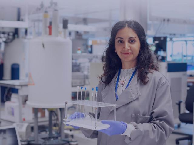 Woman in lab coat holding test tubes
