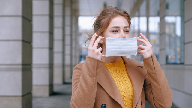 Young woman putting a mask over her mouth and nose