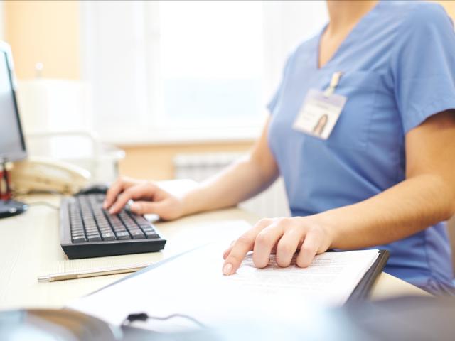 Woman in scrubs using computer