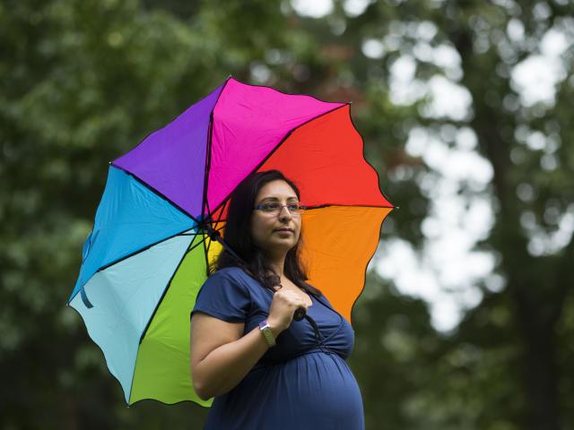 Pregnant woman holding colourful umbrella