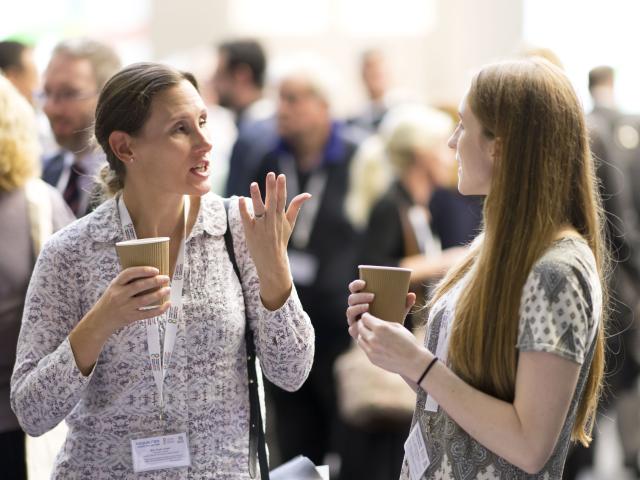 two people talking at an even with cups of coffee