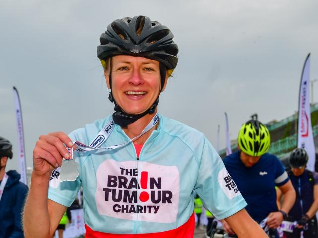 Ceri Battle holding a medal at charity ride