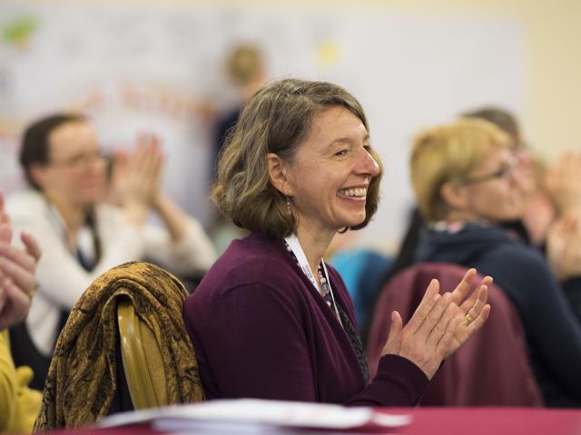 Smiling woman clapping in audience of an event