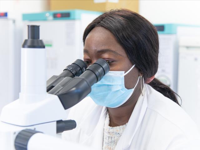 Clinical researcher looking into microscope
