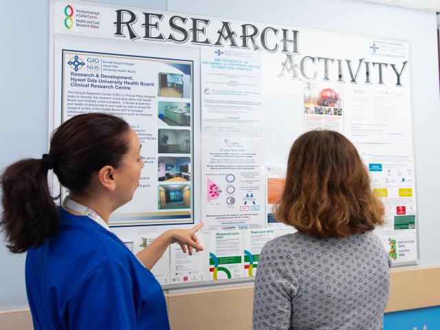 Two people looking at a research activity board