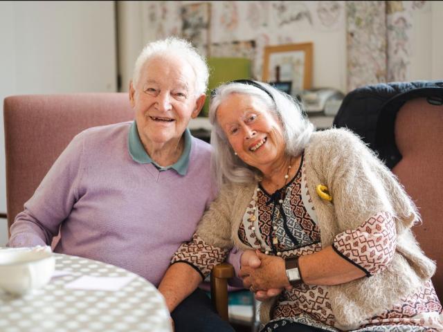 Two older people sat together and smiling
