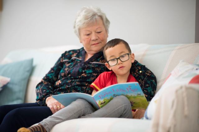 older woman reading with a boy on a sofa