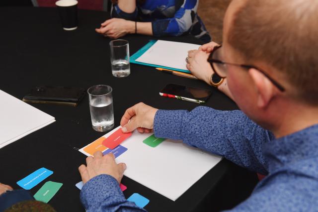 Man adding coloured paper to white sheet of paper