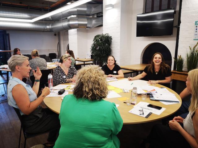 A group of women sitting around a table and having a discussion. 