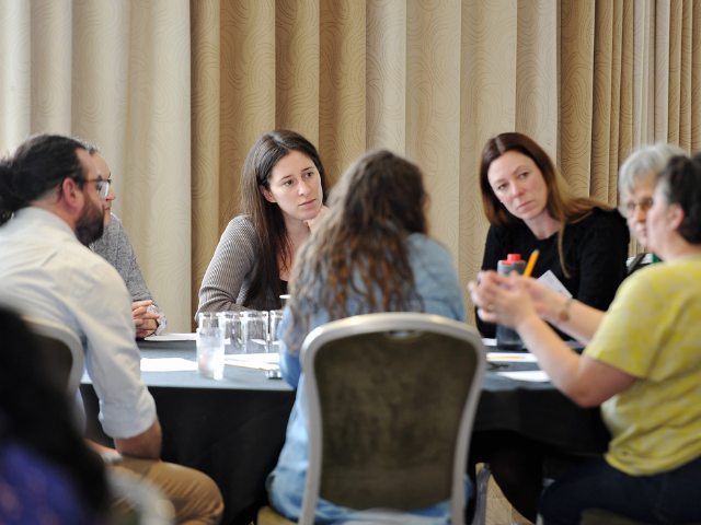 A group of people sitting around a table a discussing research. 