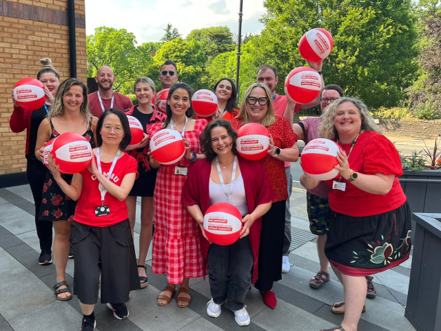 Group of people dressed in red holding red beach balls