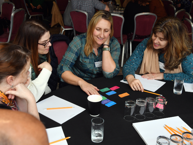 A group of people sitting around a table a discussing research. 