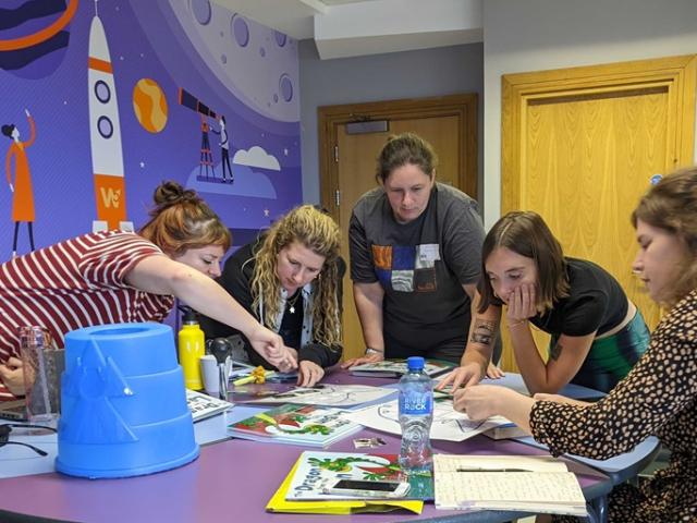 five female scientists sat around a table working together