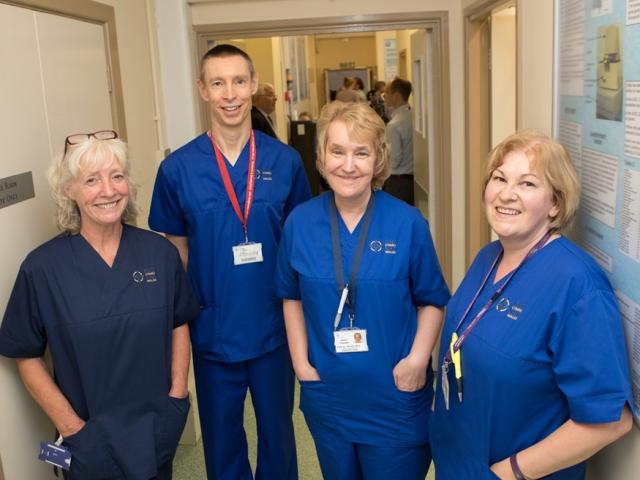 Four research nurses stood smiling in a corridor