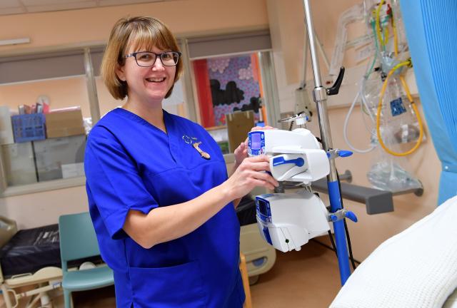 A nurse wearing blue, smiling at the camera