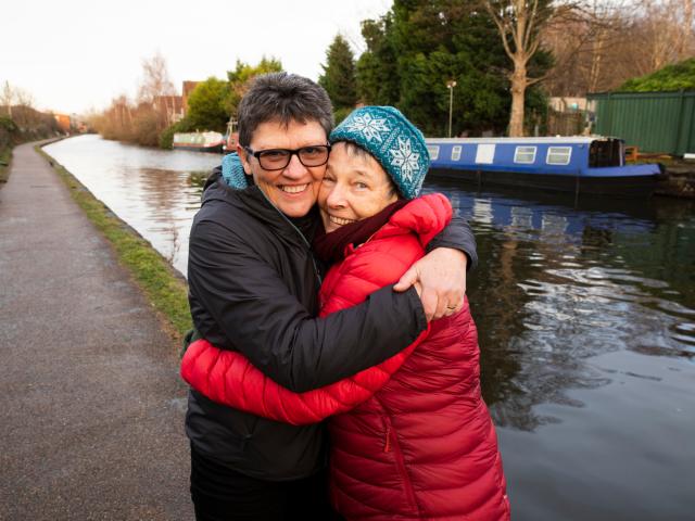 Two women hugging by a river. 