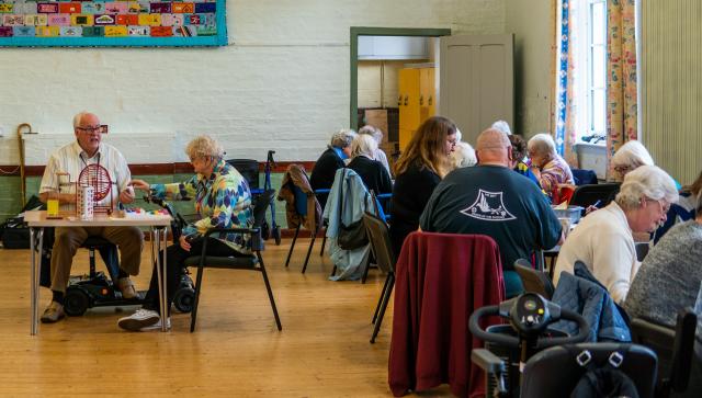 Room of older people sat at tables playing bingo