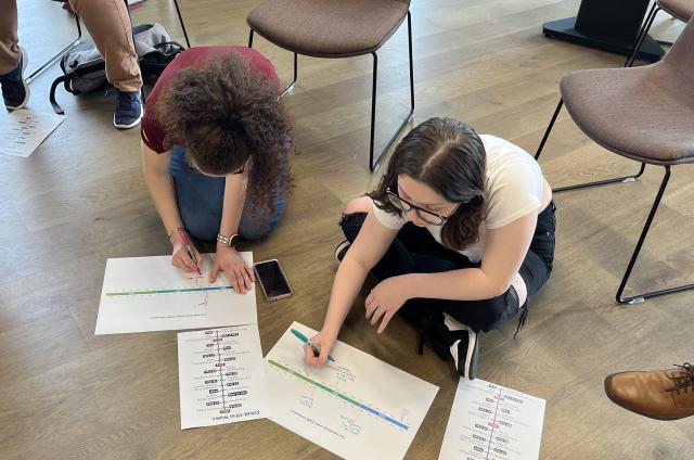 Young people sat on floor writing