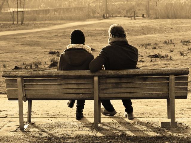 two people sat on a bench talking