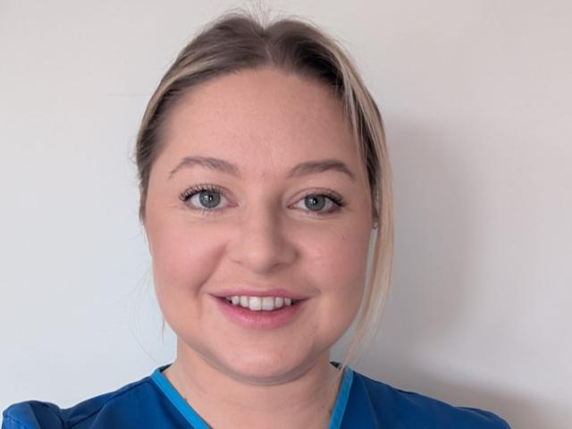 a_woman_in_blue_scrubs_smiling