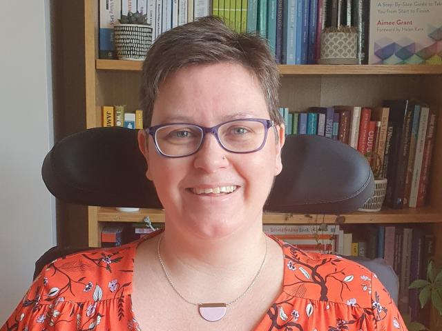 a_woman_smiling_in_front_of_a_bookcase