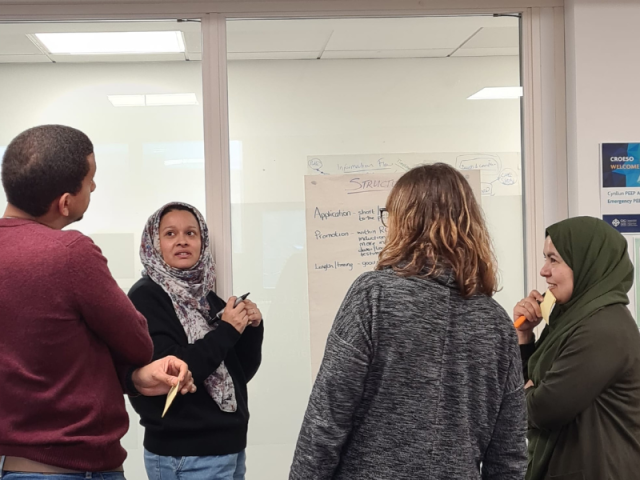 A group of people sitting around a table a discussing research.