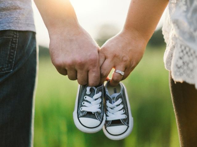 two_people_holding_baby_shoes