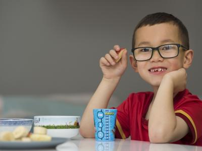 Young boy wearing glasses eating fruit