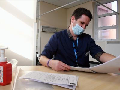 Man wearing a mask reading some papers