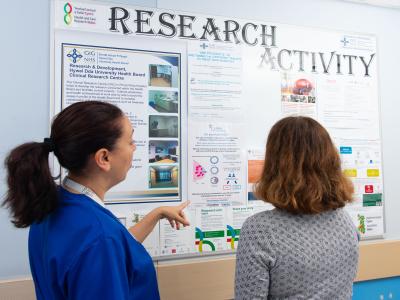 Research nurse looking at research activity on hospital display board
