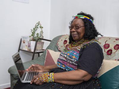 A black woman in traditional clothing using a laptop. 