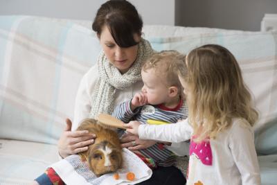a mother with two children playing with a guinea pig