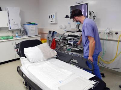 A male nurse preparing a bed for a patient in a hospital room.