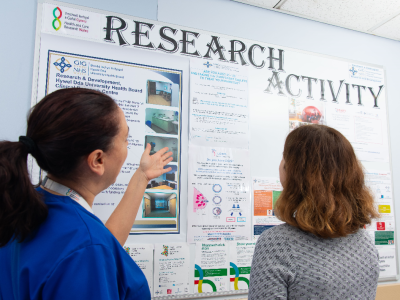Two research staff looking at the research activity board