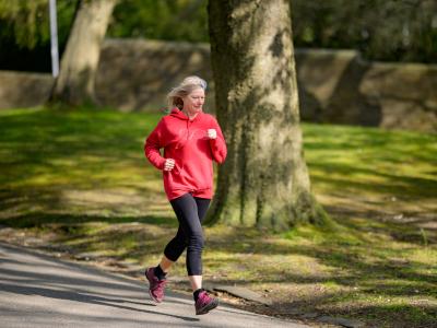 An elderly woman running in a park.