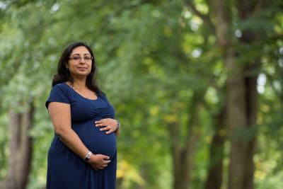 a pregnant woman standing in a wood