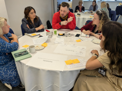 A group of people sitting around a table a discussing research. 