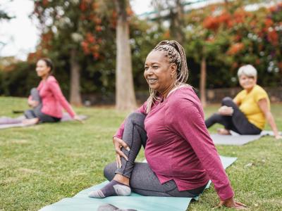 three women exercising on the grass in a park