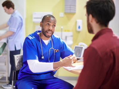 Two men talking one is dressed in scrubs and the other is in a red shirt